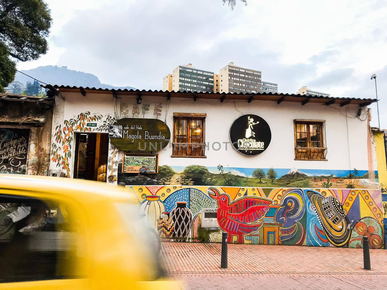 Street view of cafe in Bogota, Colombia with taxi and art mural. by jyurinko