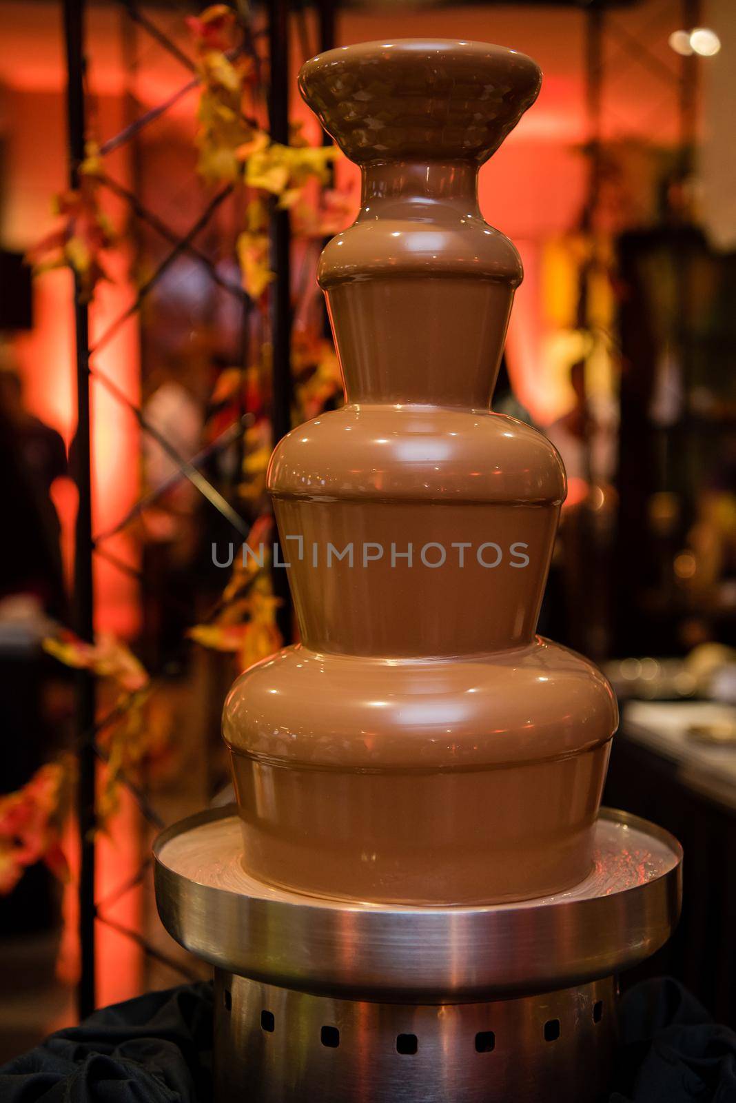 Chocolate fountain with layers and warm colored background by jyurinko