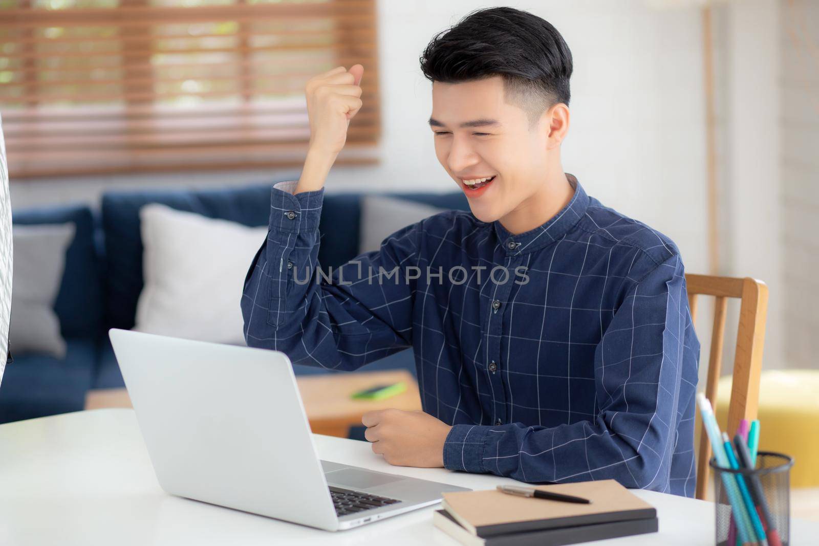Happy young businessman work on laptop computer finish with excited and success on desk at home, business man using notebook with achievement and surprised, freelance or employee, satisfied and glad.