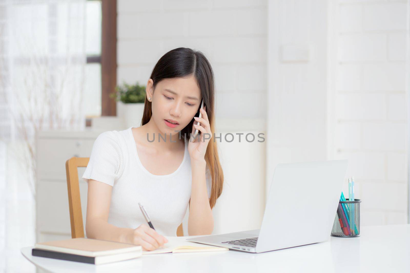 Young asian woman working on laptop computer and talking smartphone having stress and upset at home, girl having problem and worried, frustrated and unhappy, business and communication concept. by nnudoo