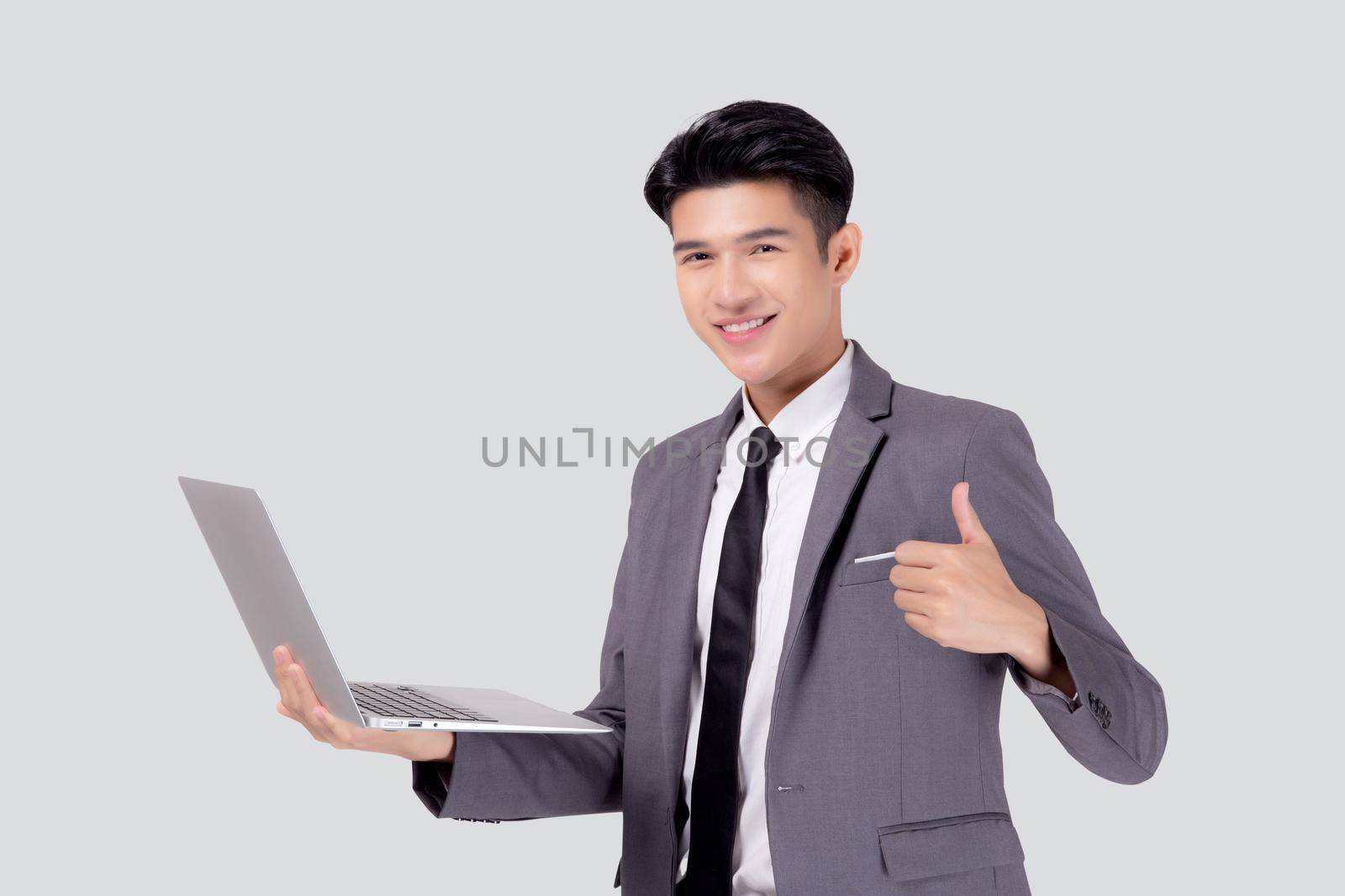 Young asian business man standing work on laptop computer to internet online isolated on white background, businessman confident and notebook, freelance with success, marketing and communication. by nnudoo
