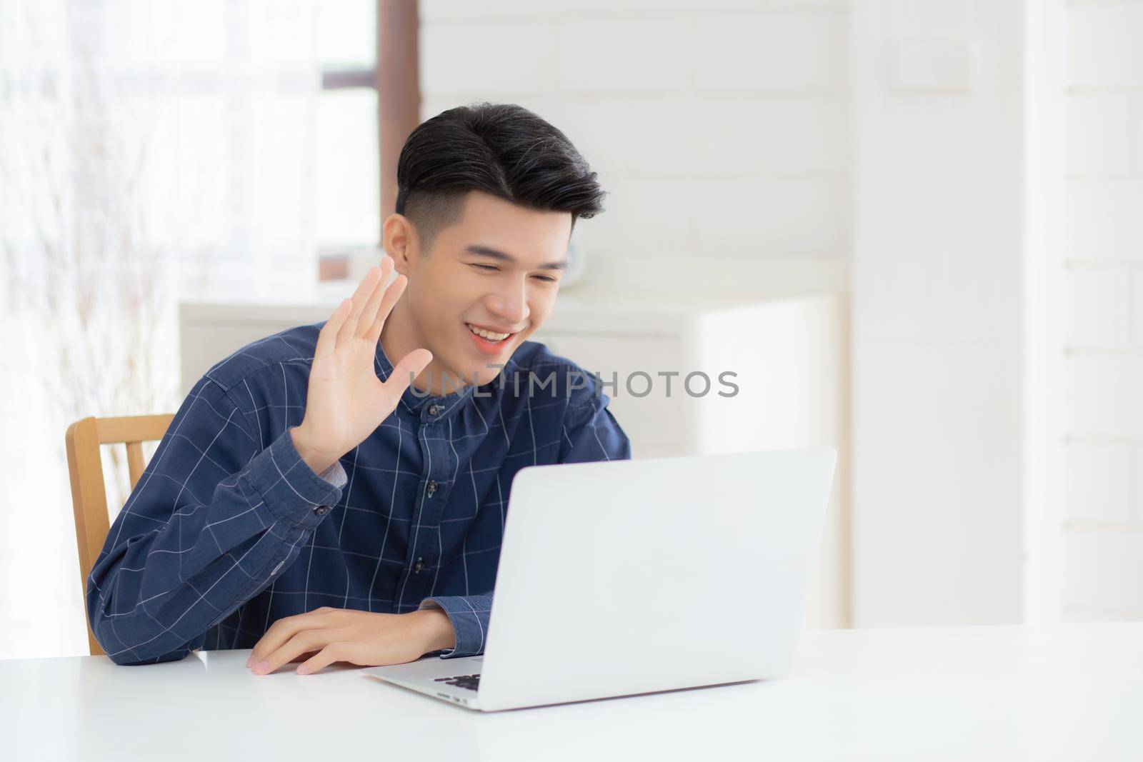 Young asian business man using laptop computer for video call online hello and communicate work from home, male conference with notebook and say hi, social distancing, communication concept.