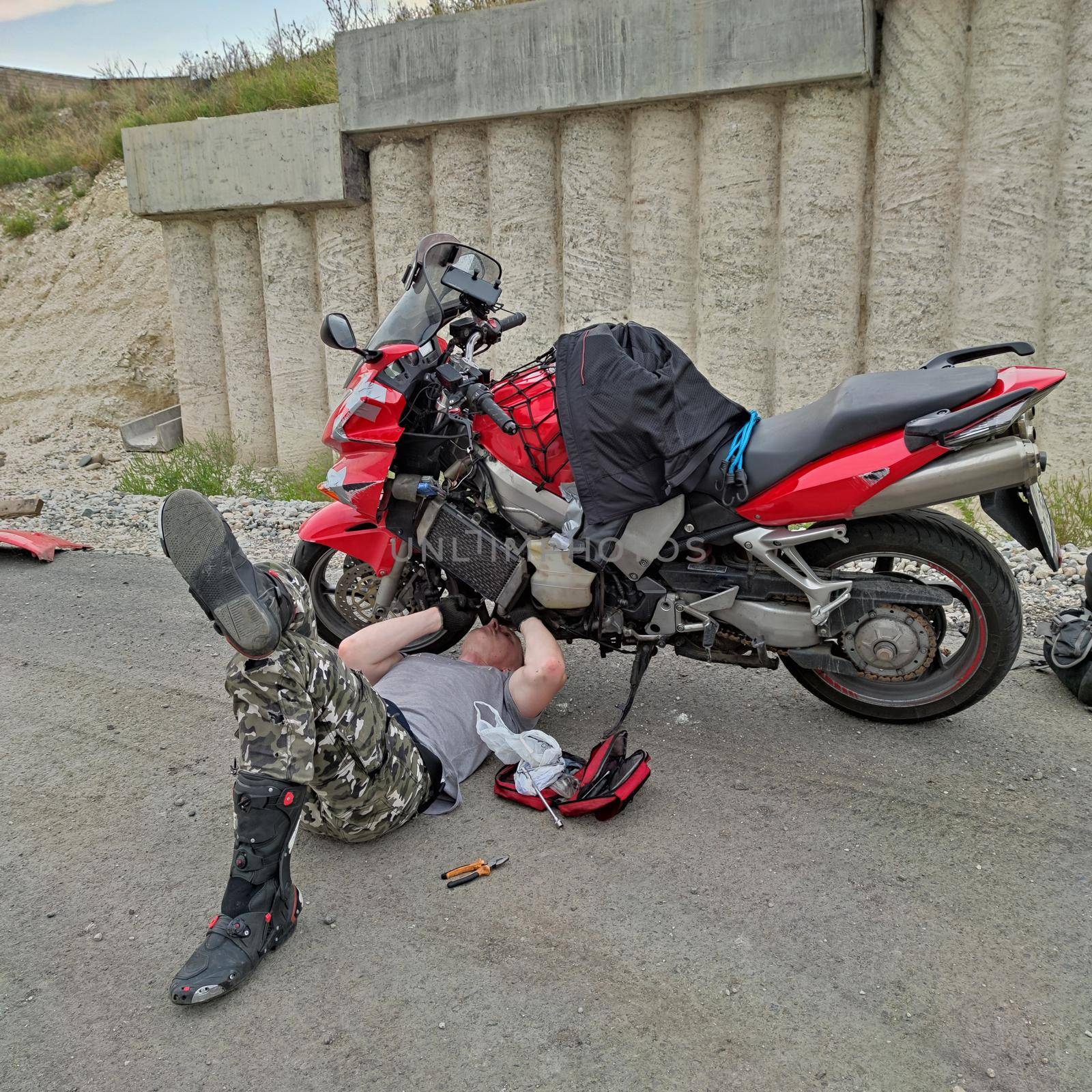 Man repair motorbike on road by VITAL_ML