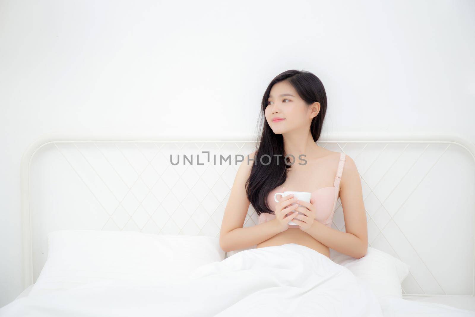 Beautiful young asian sexy woman in underwear drinking coffee in the morning on bed at bedroom, asia girl with seductive figure fit drinking beverage for relax after wake up, lifestyle concept.