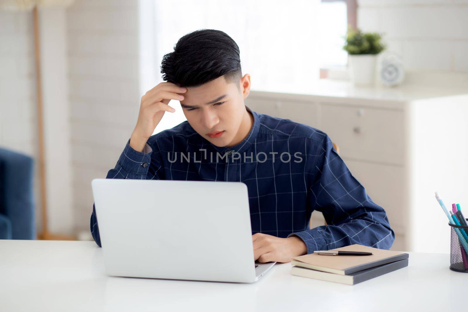 Young asian business man headache during working on laptop computer with deadline on desk at home, businessman with failure exhausted and tired, stress and worried, frustrated and unsuccessful. by nnudoo