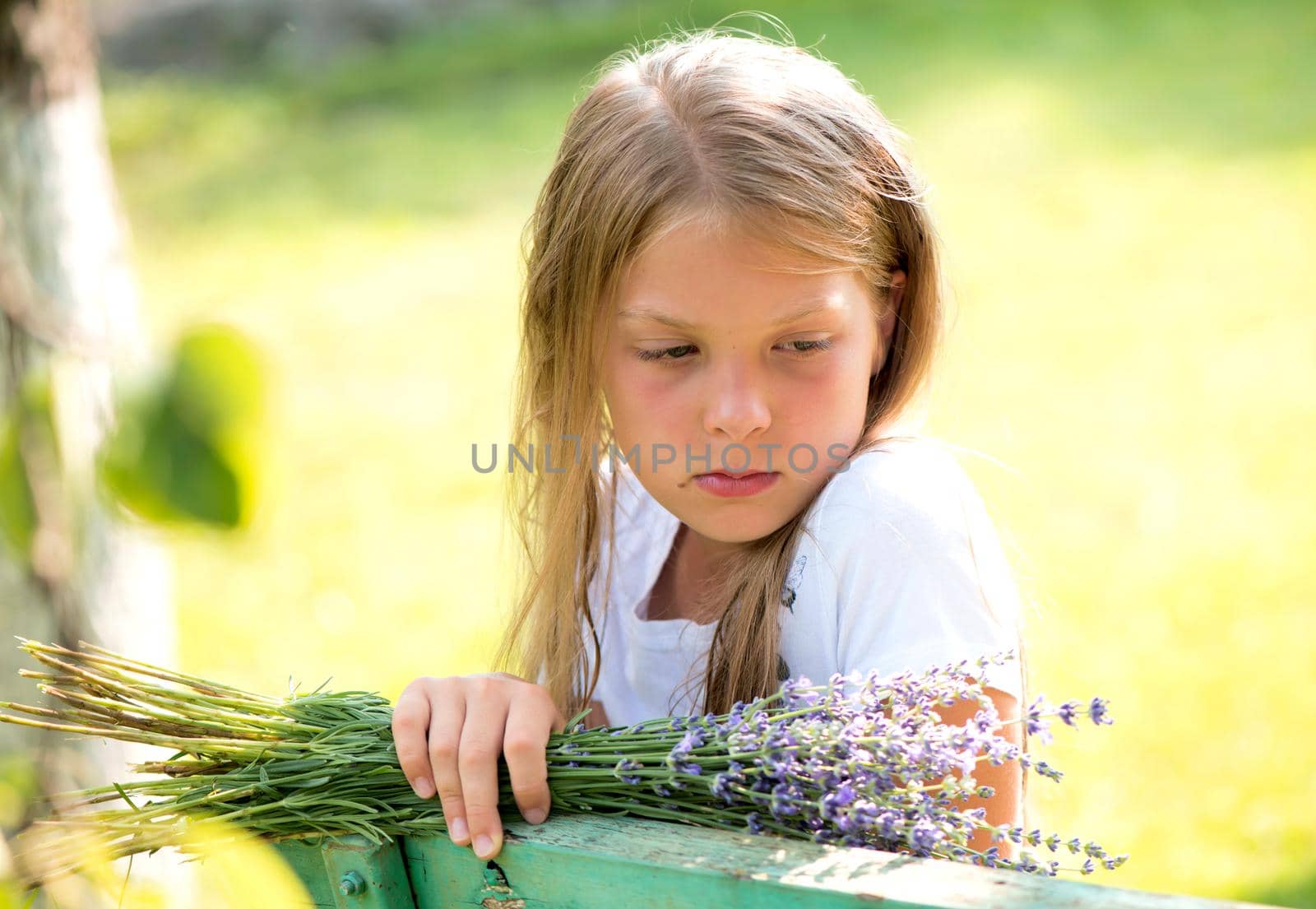 pensive girl sits on a bench with a bouquet of flowers near a private house by aprilphoto