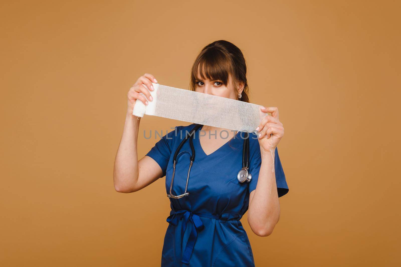 a female doctor in a white coat holds twisted gauze bandages for dressing wounds on a brown background by Lobachad