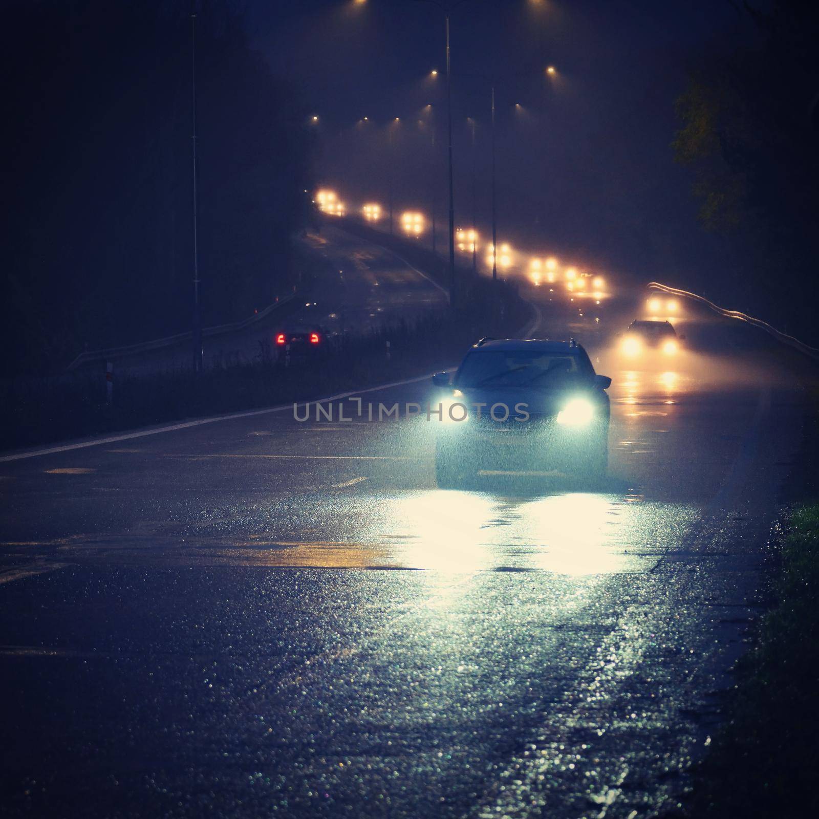 Car on the road in the fog. Autumn landscape - dangerous road traffic in winter season. by Montypeter