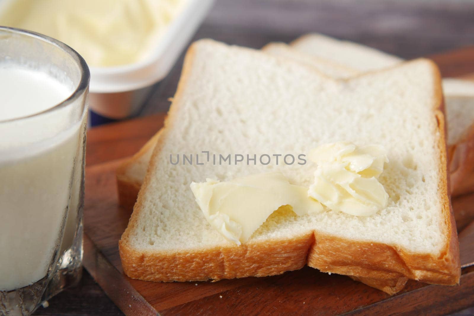 slice of butter and whole meal bread on chopping board .