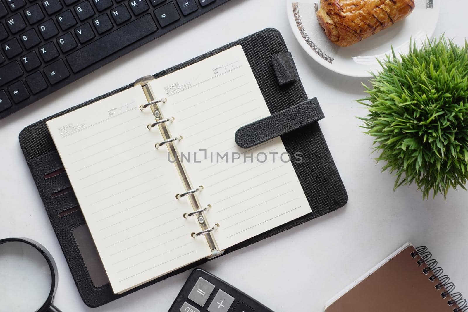 high angle view of open notepad and office stationary on white .