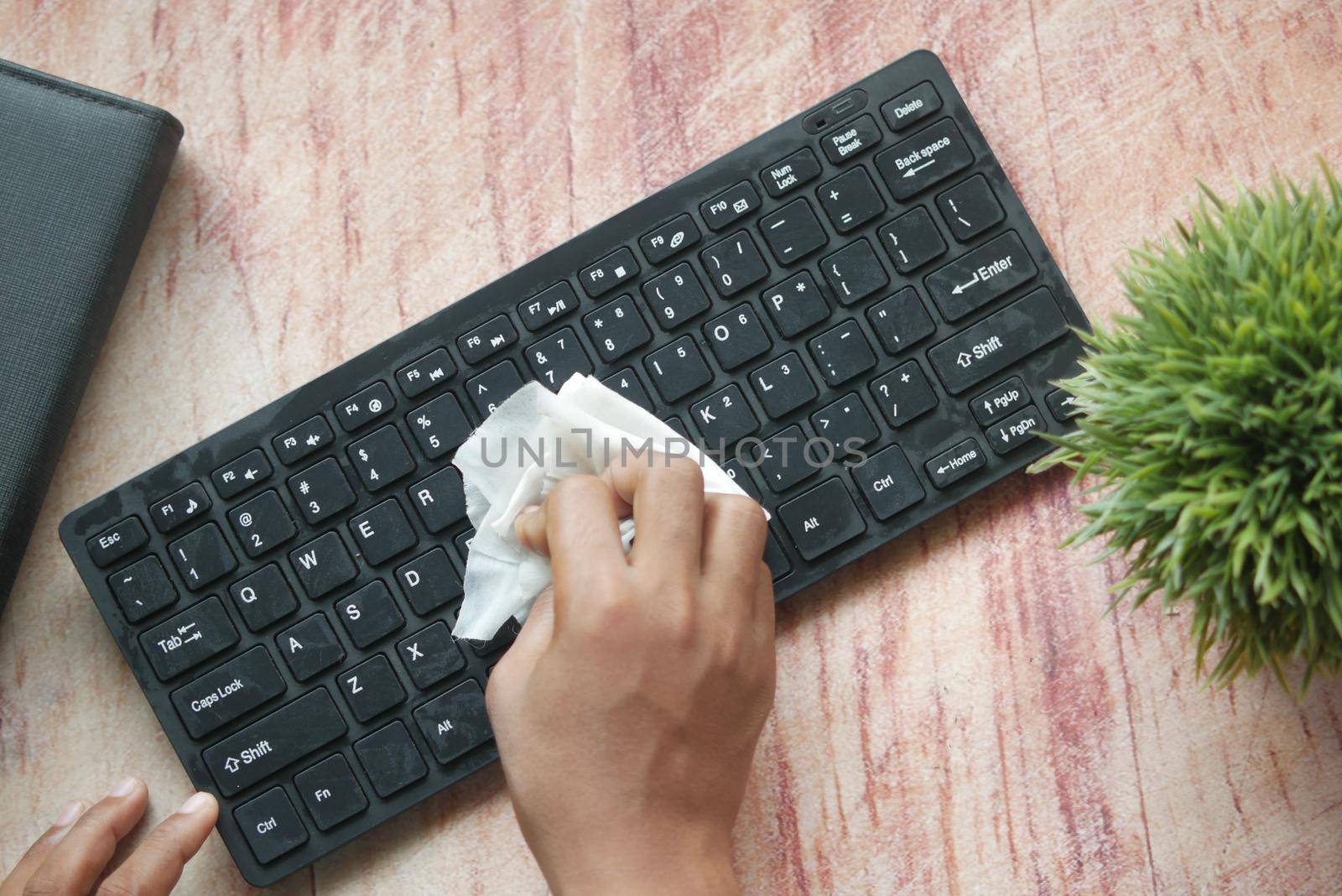 close up of person hand cleaning keyboard with cloth .