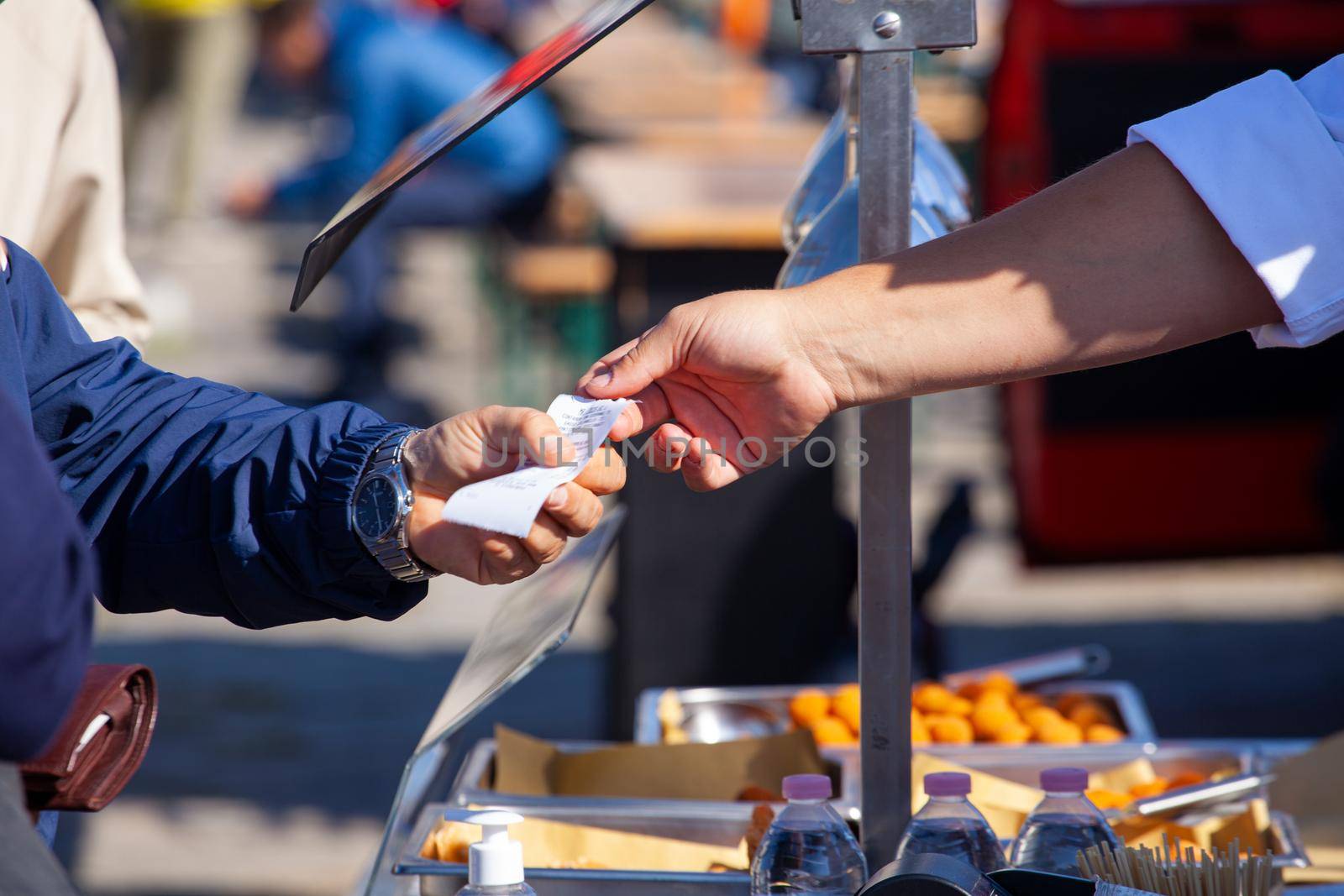 Hands of the shopkeeper who passes the sales receipt to the buyer by bepsimage