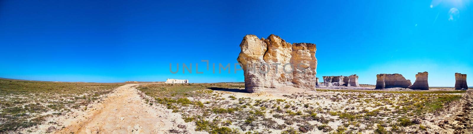 Panorama of dirt road in desert with large vertical rock obelisks by njproductions