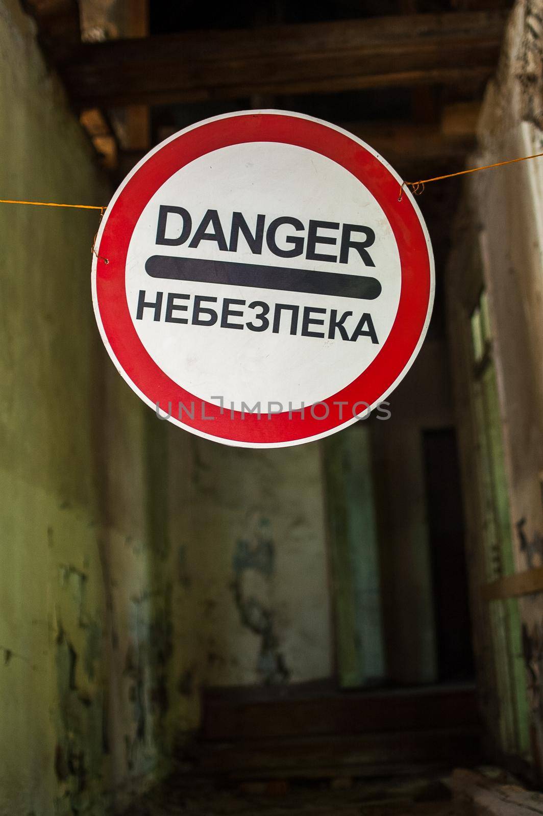 Old wrecked house with 'Danger' in English and in Ukrainian warning sign, abandoned building, uninhabitable place by balinska_lv