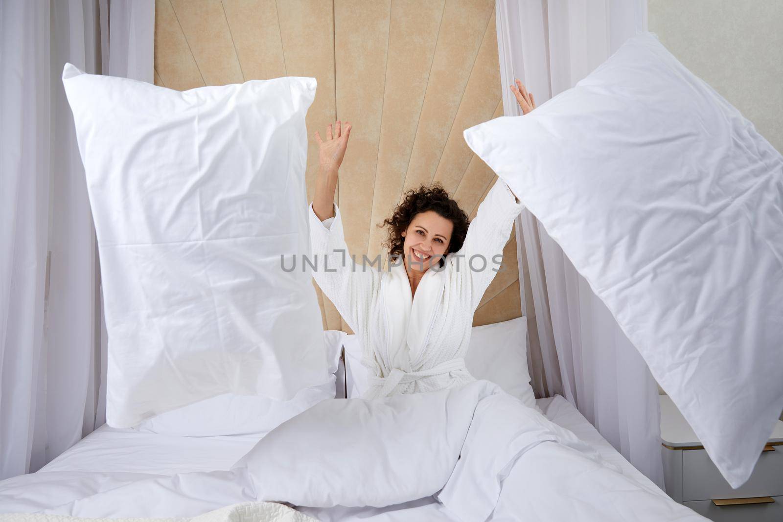 Playful woman throwing a pillow, Having fun on weekend at home
