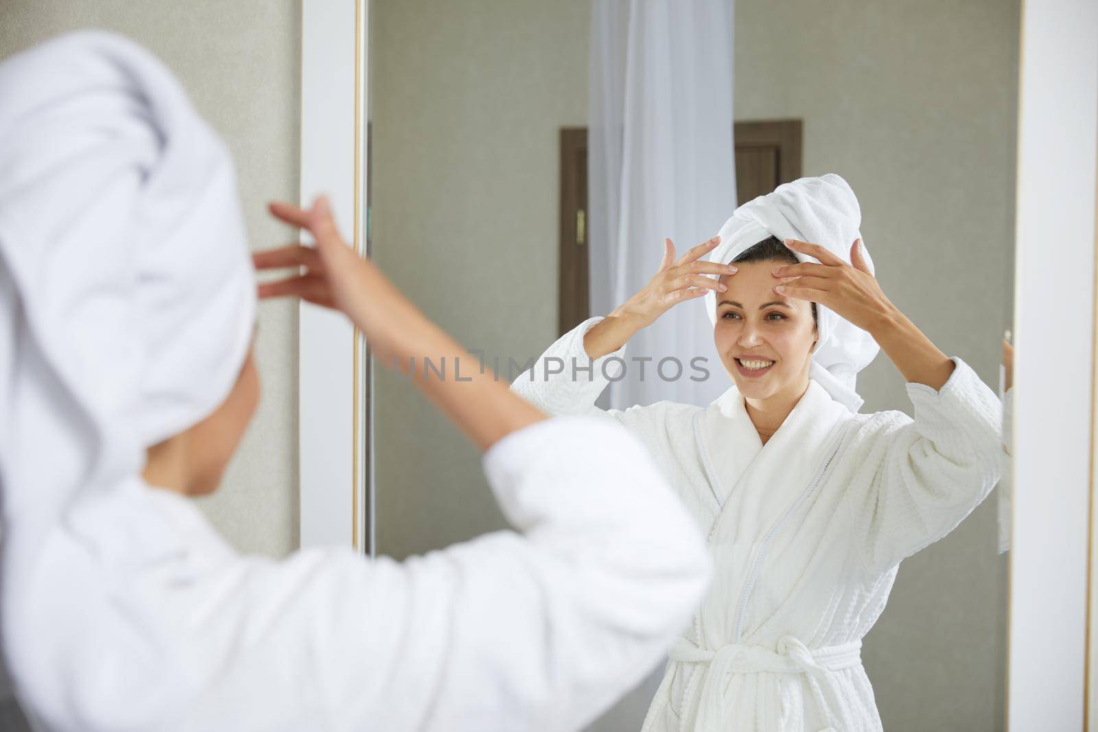 Young girl doing facial gymnastics self massage and rejuvenating exercises in the morning after taking shower. Face building for skin and muscles lifting by Mariakray