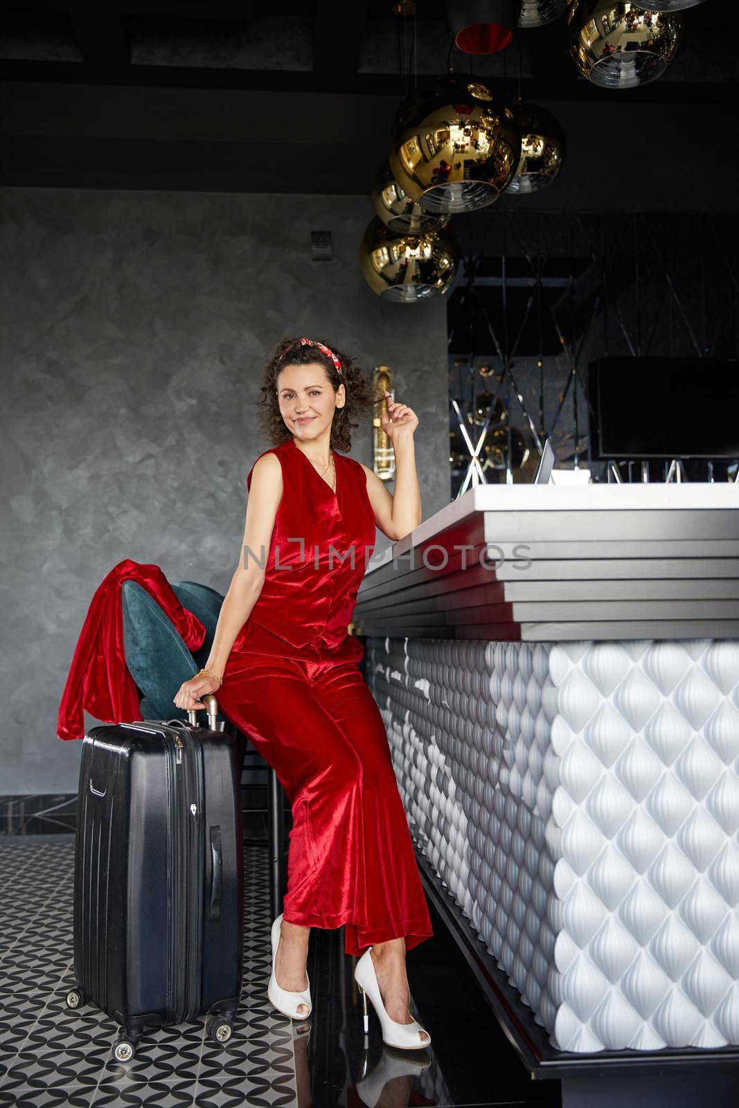 Young pretty businesswoman sitting in hotel bar with suitcase. Business travel concept by Mariakray
