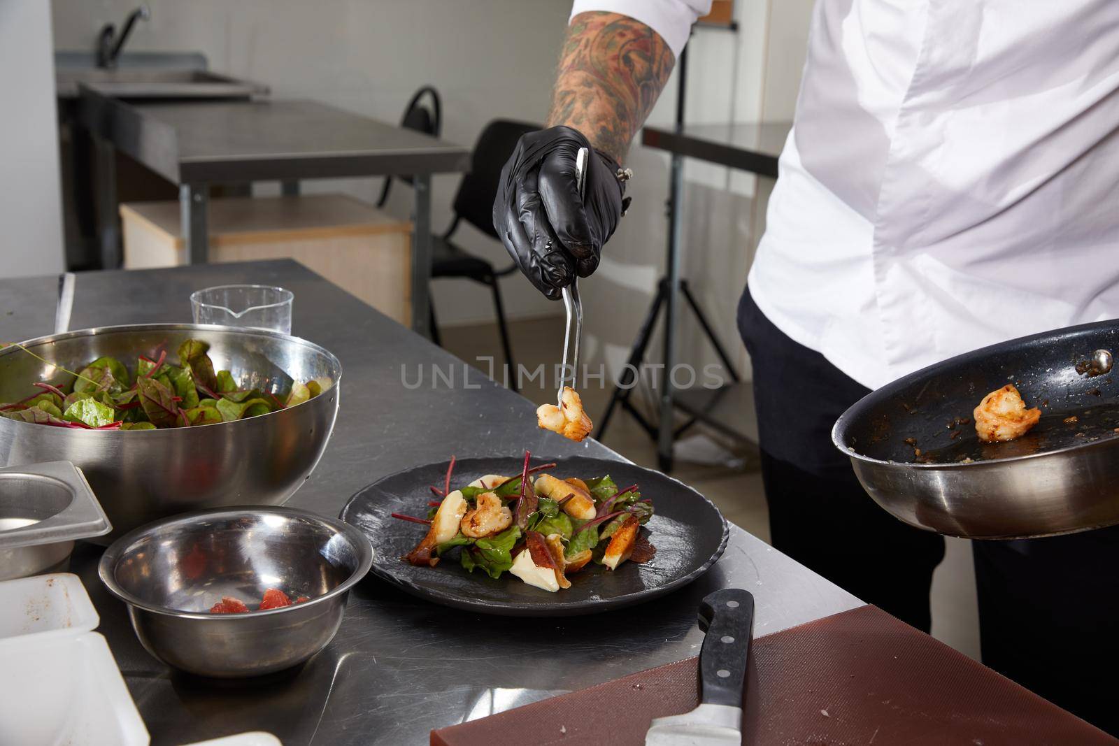Close-up of chef hands preparing salad in a restaurant kitchen