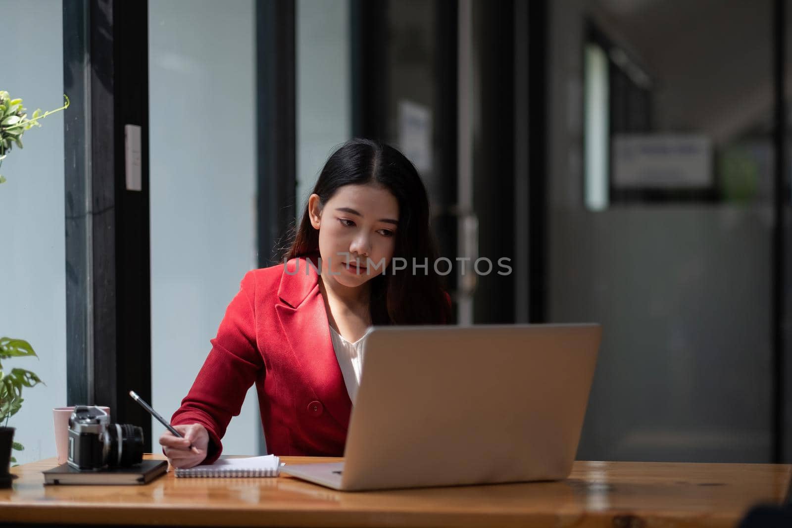 Asian business woman working on laptop computer and taking note at the office. by nateemee