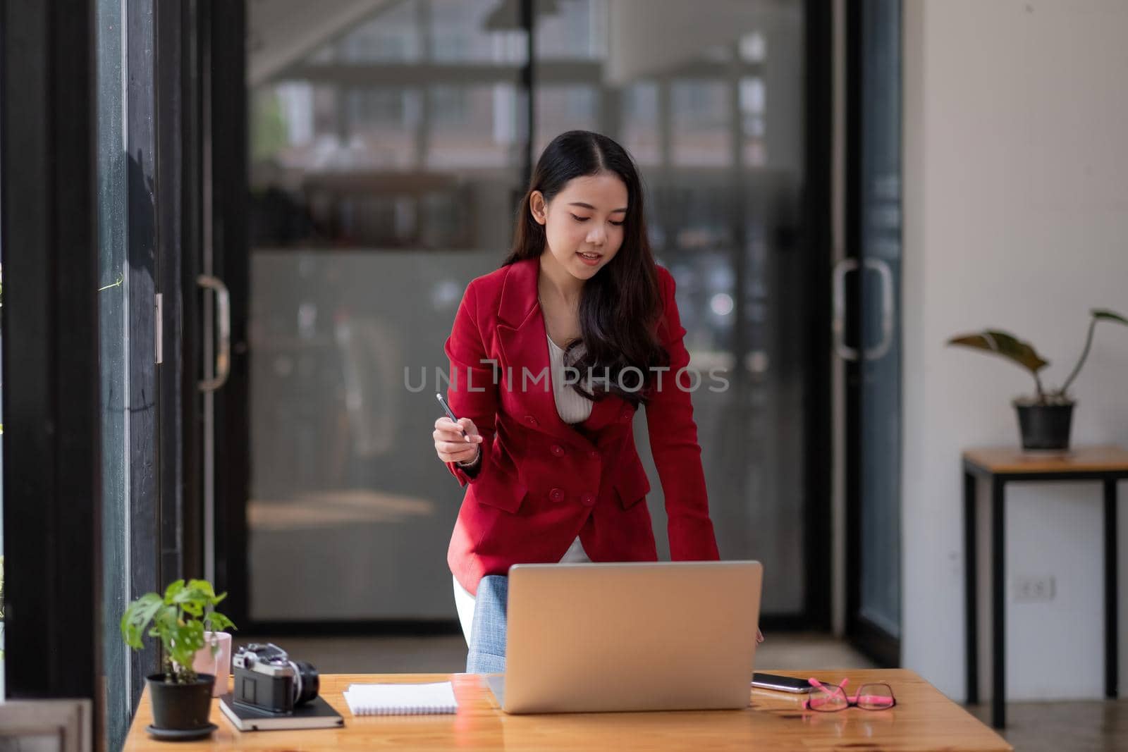 Charming asian businesswoman standing working on laptop in office by nateemee