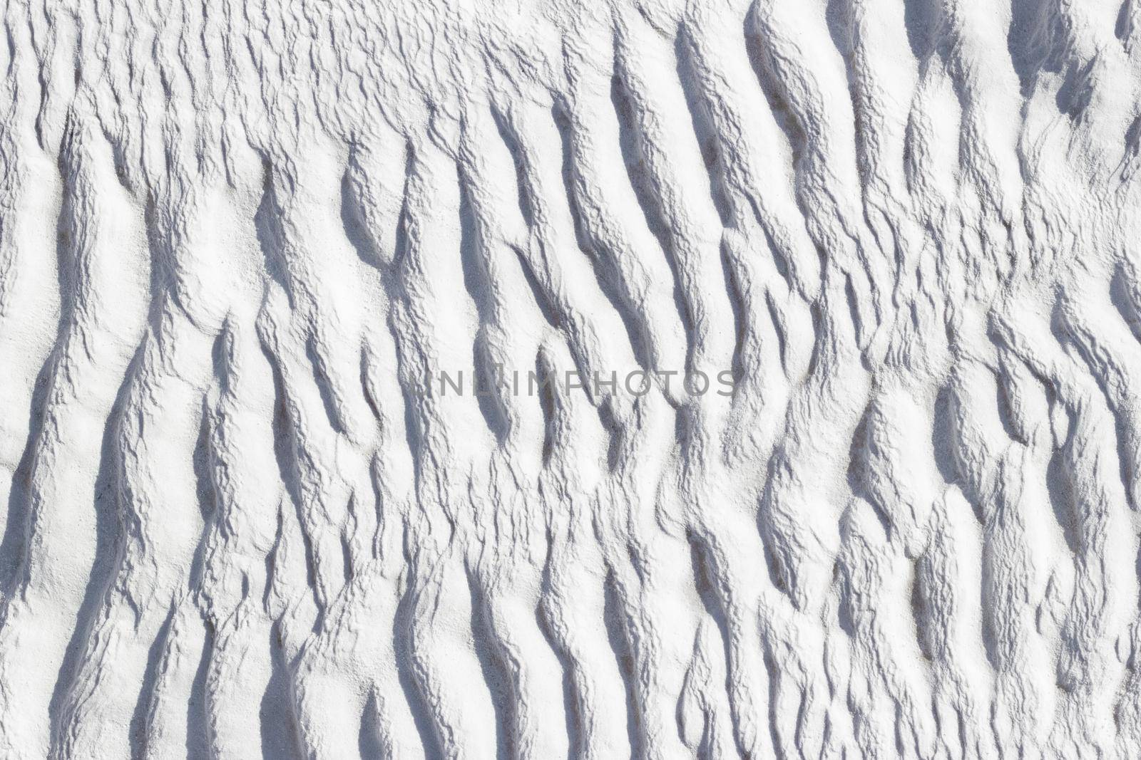 Ribbed abstract texture of Pamukkale calcium travertine in Turkey, asymmetric pattern close-up.