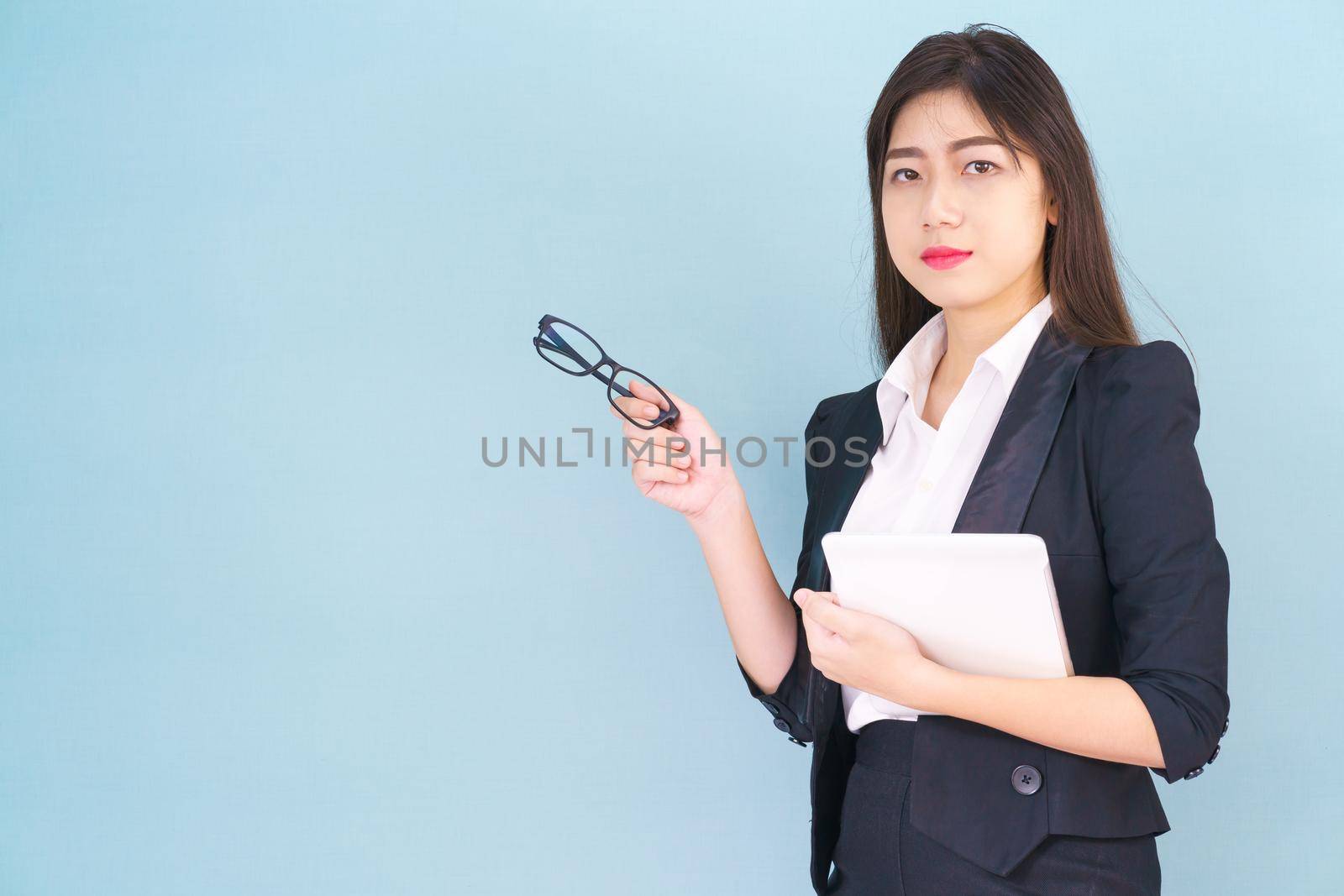 Young Asain women in suit standing using her digital tablet against blue background