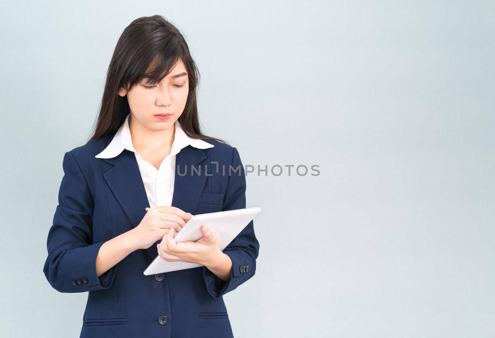 Woman in suit using digital tablet on gray background by stoonn