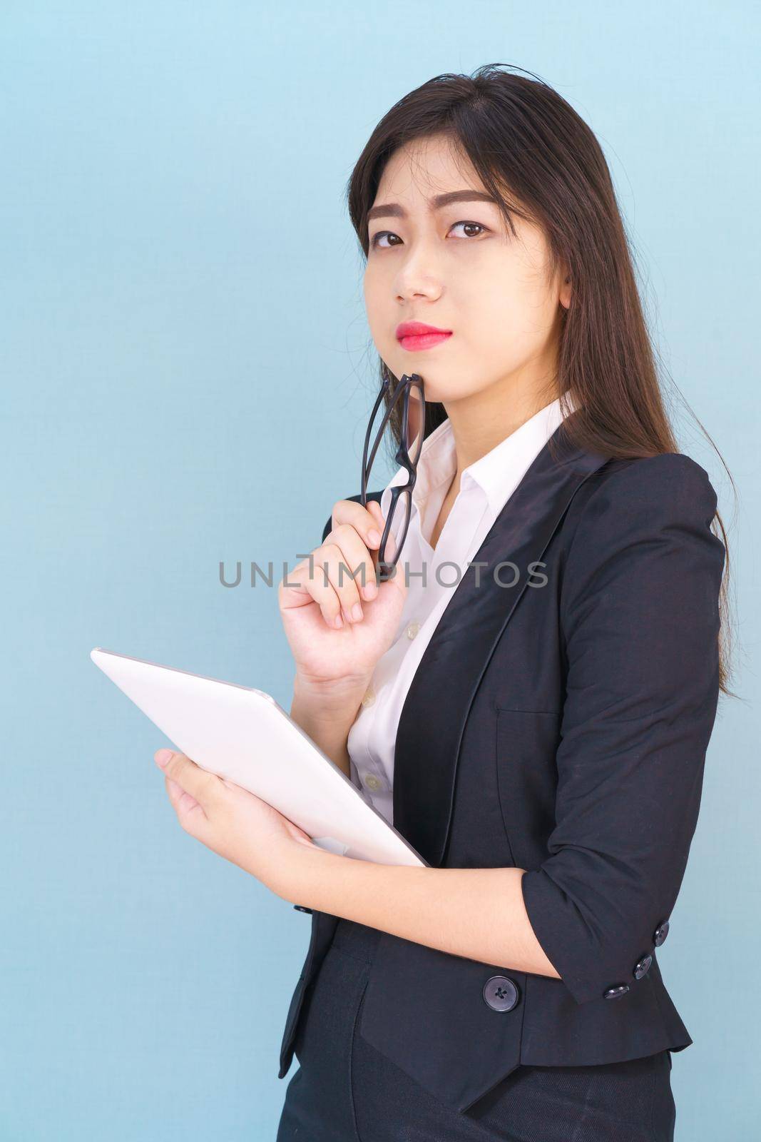 Young Asain women in suit standing using her digital tablet against blue background