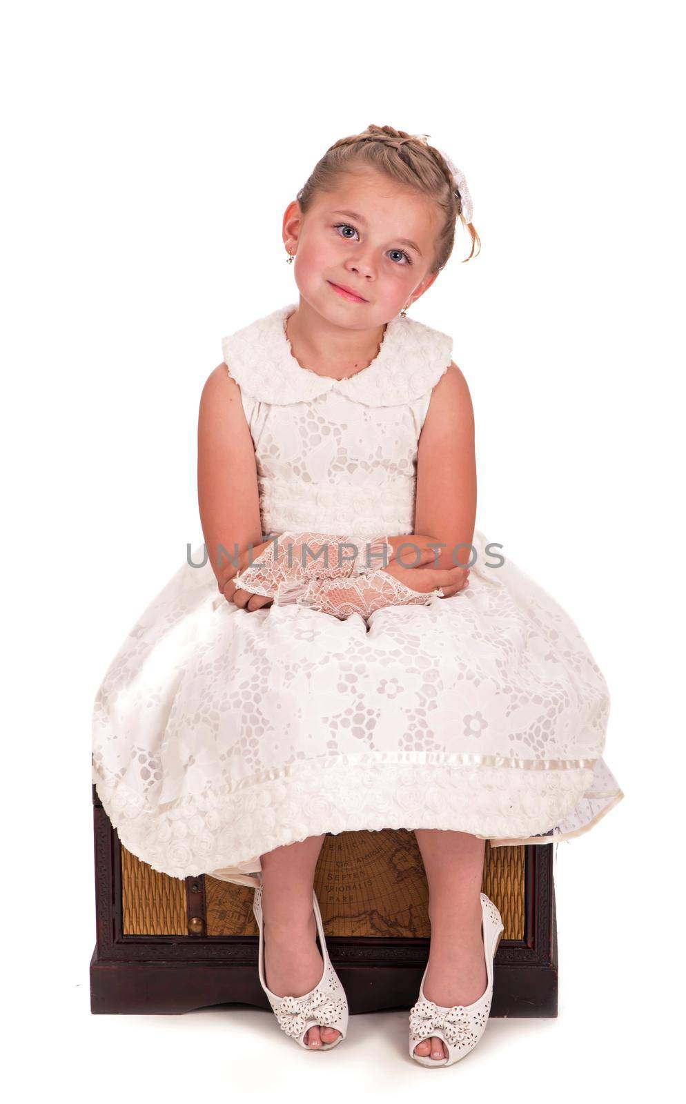 girl and a chest with books. little girl looking inside a trunk with surprise on white background by aprilphoto