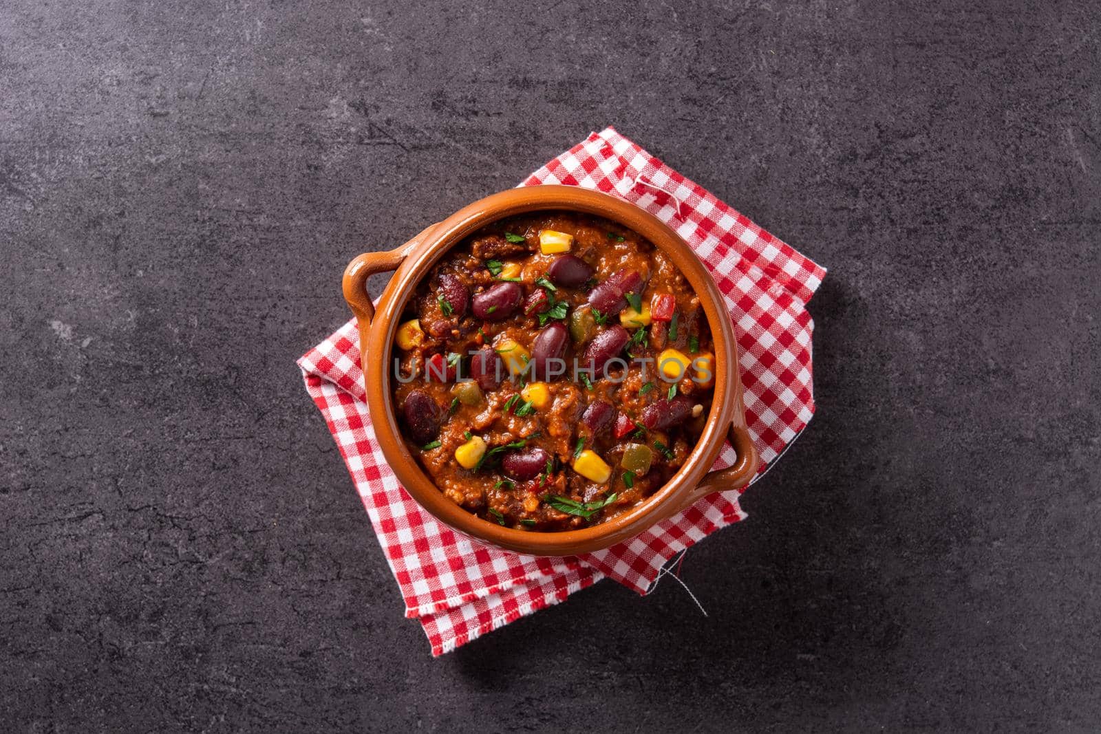 Traditional mexican tex mex chili con carne in a bowl on black background.