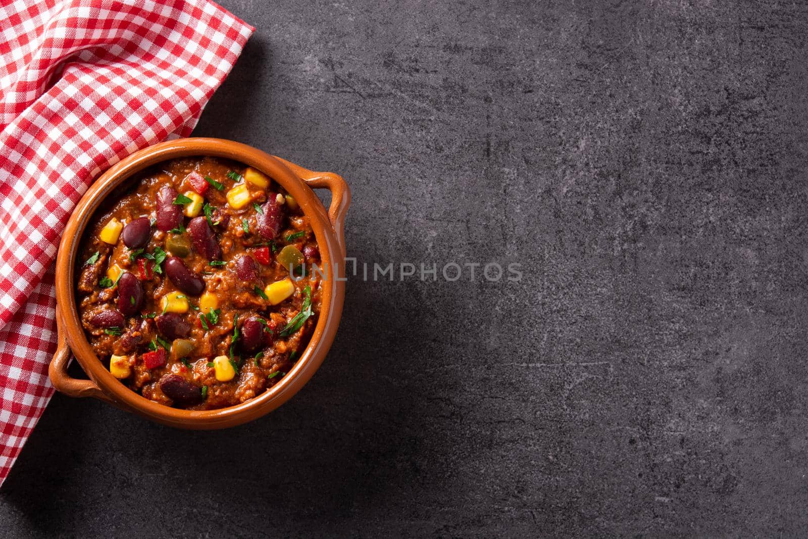 Traditional mexican tex mex chili con carne in a bowl on black background.