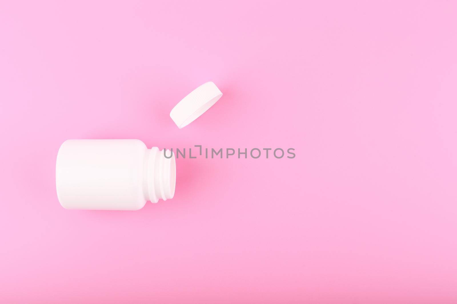 Minimal flat lay with white opened medication bottle on saturated pinkish purple bright background with copy space. Concept of vitamins or supplements