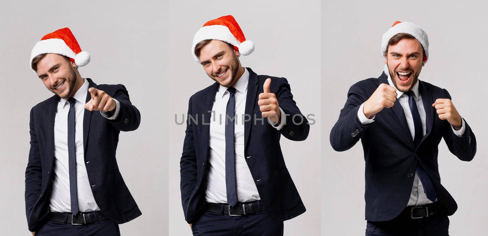 Young handsome caucasian guy in business suit and Santa hats stands on white background in studio smilie and showing thumbs up. by andreonegin