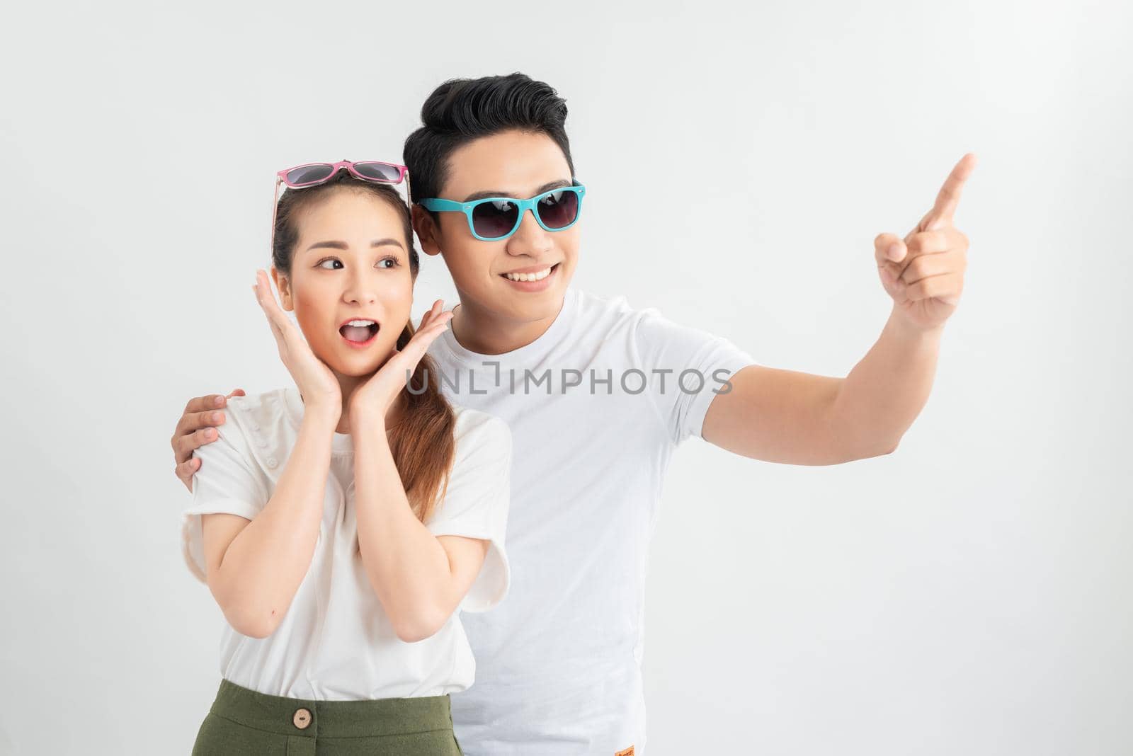 Portrait of happy couple isolated on white background, man pointing at white copy space