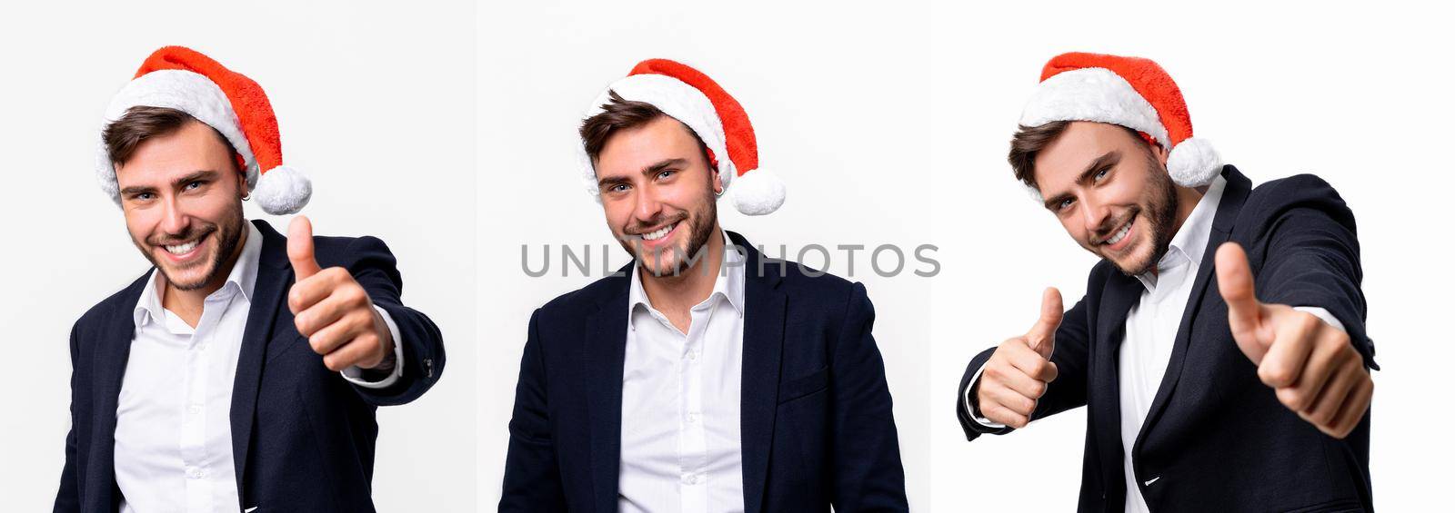 Young handsome caucasian guy in business suit and Santa hats stands on white background in studio smilie and showing thumbs up. by andreonegin