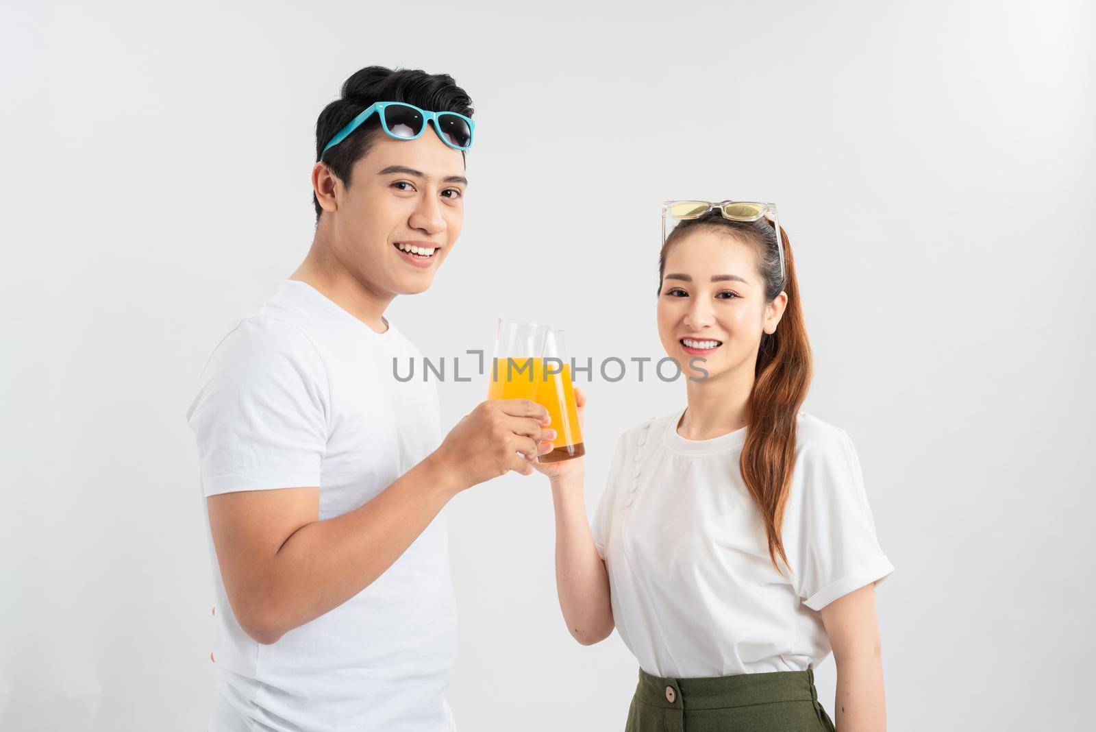 A young couple drink OJ on white background