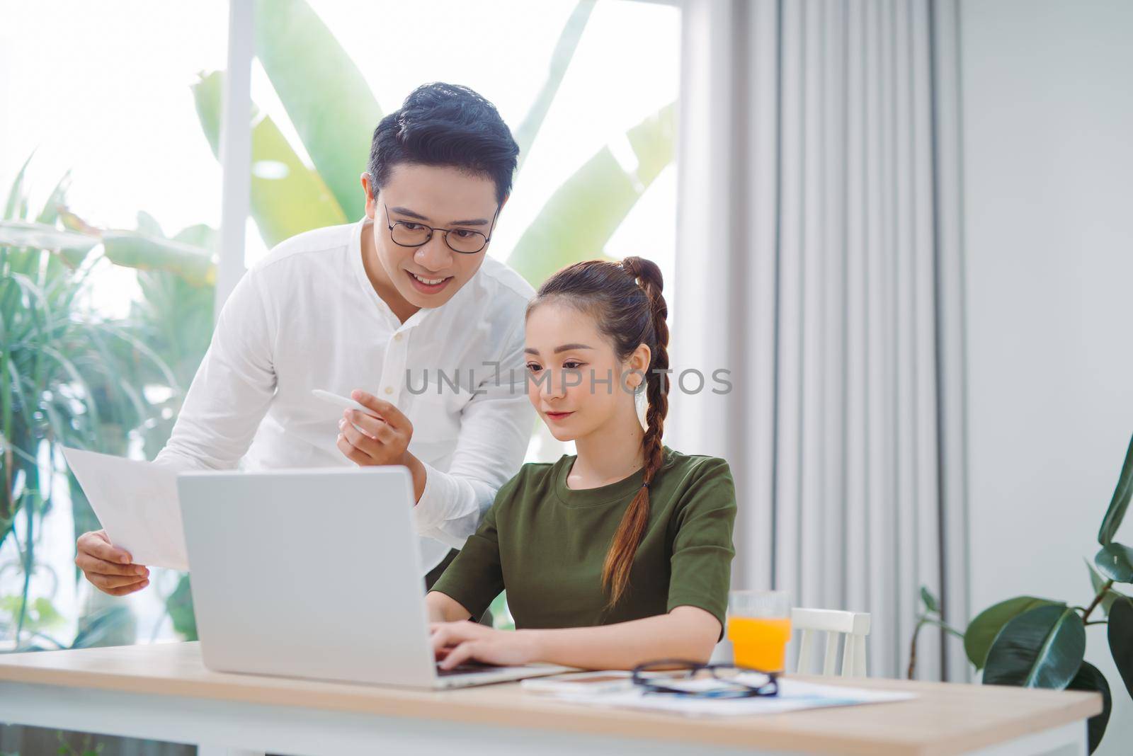 Two young business colleagues working with laptop at office