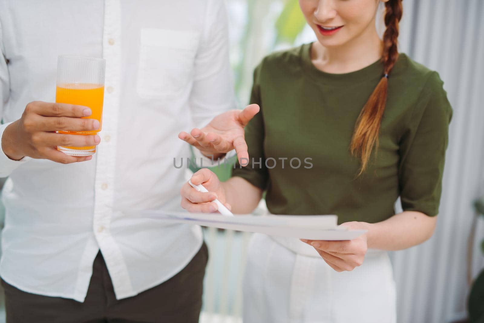 Young couple discussing things looking at laptop while having orange juice in stylish bright room