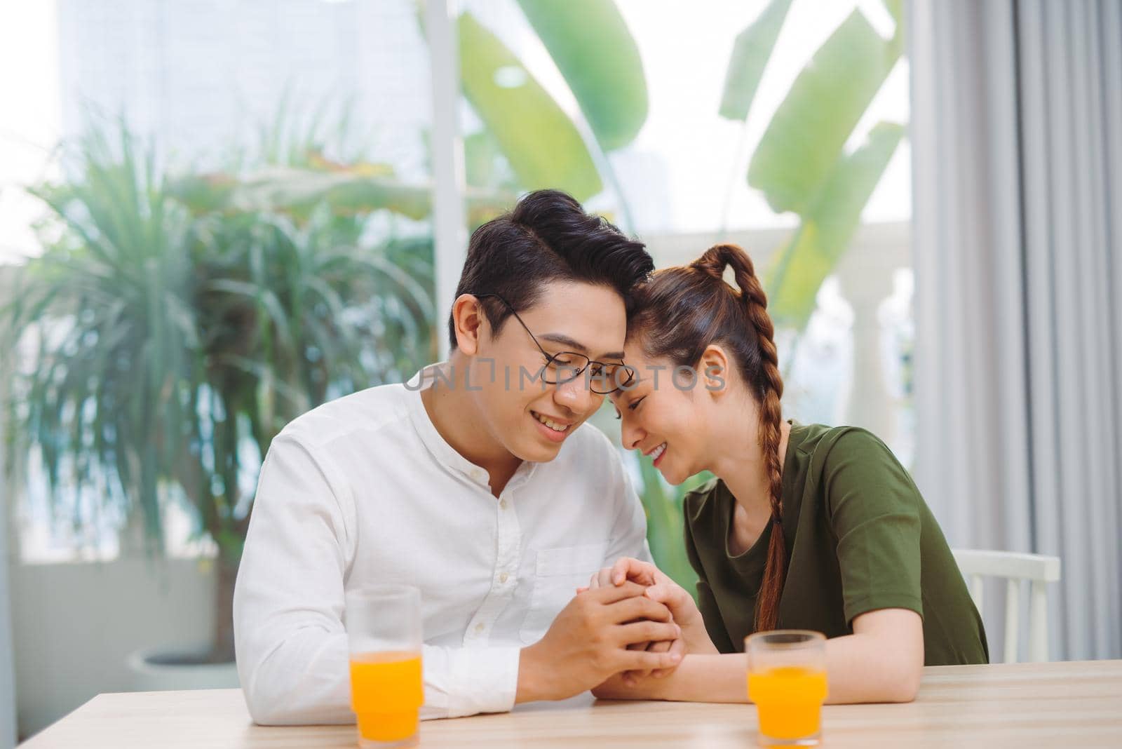 Happy young couple on a date drinking coffee and holding hands in cafe