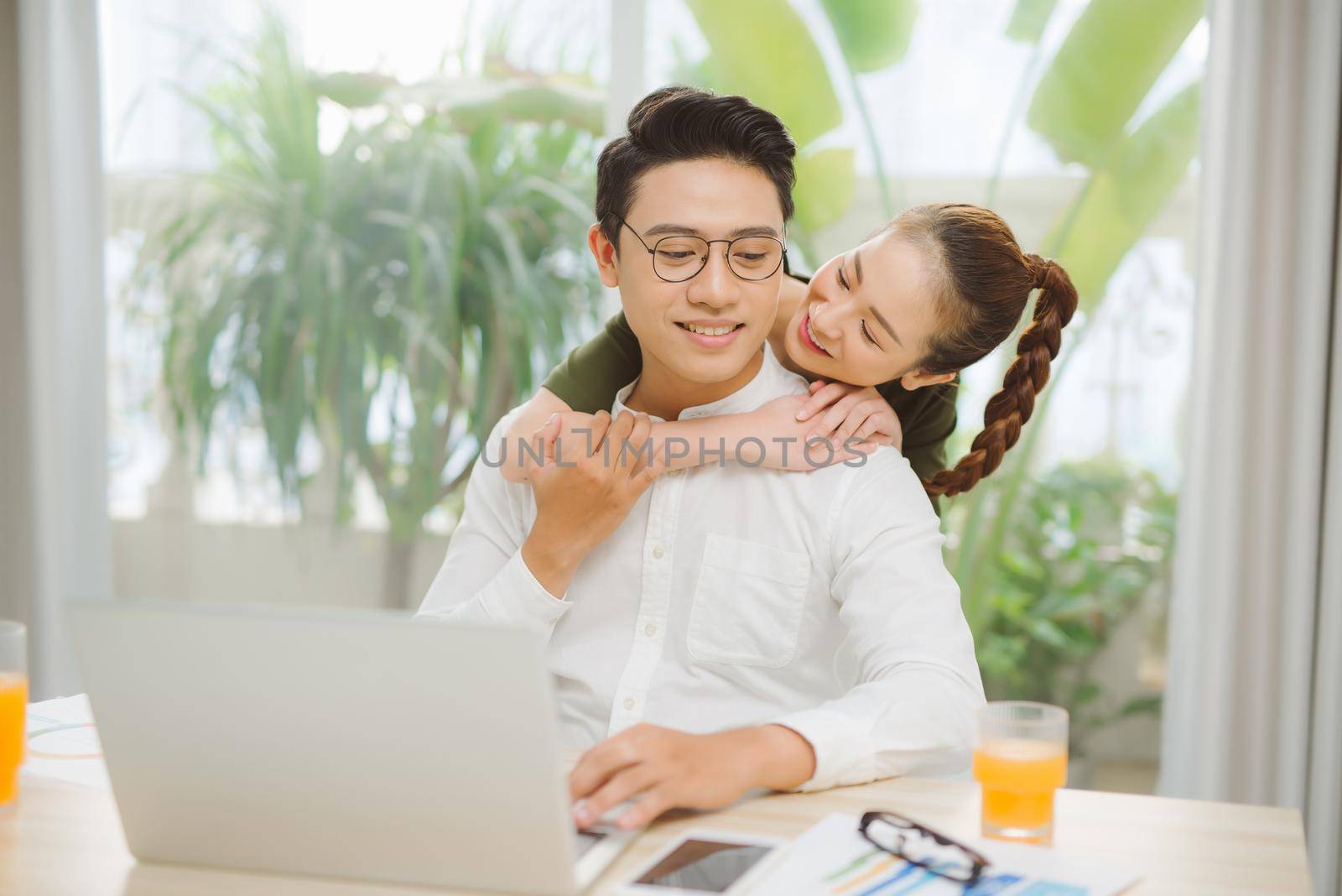 Joyful beauty couple spending time at home. Bright spacious apartment, cookies and drinks and watching laptop with surprise
