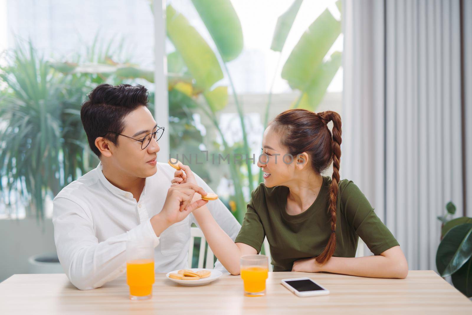 Young couple having fun while having breakfast  feeding each other