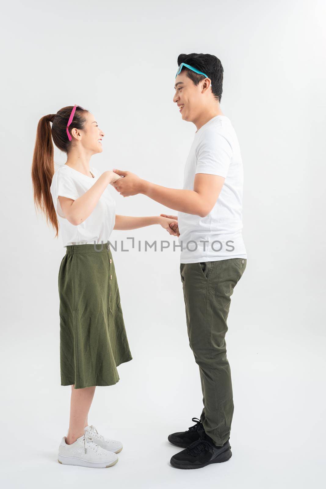 Smiling couple dancing and holding hands, isolated on white
