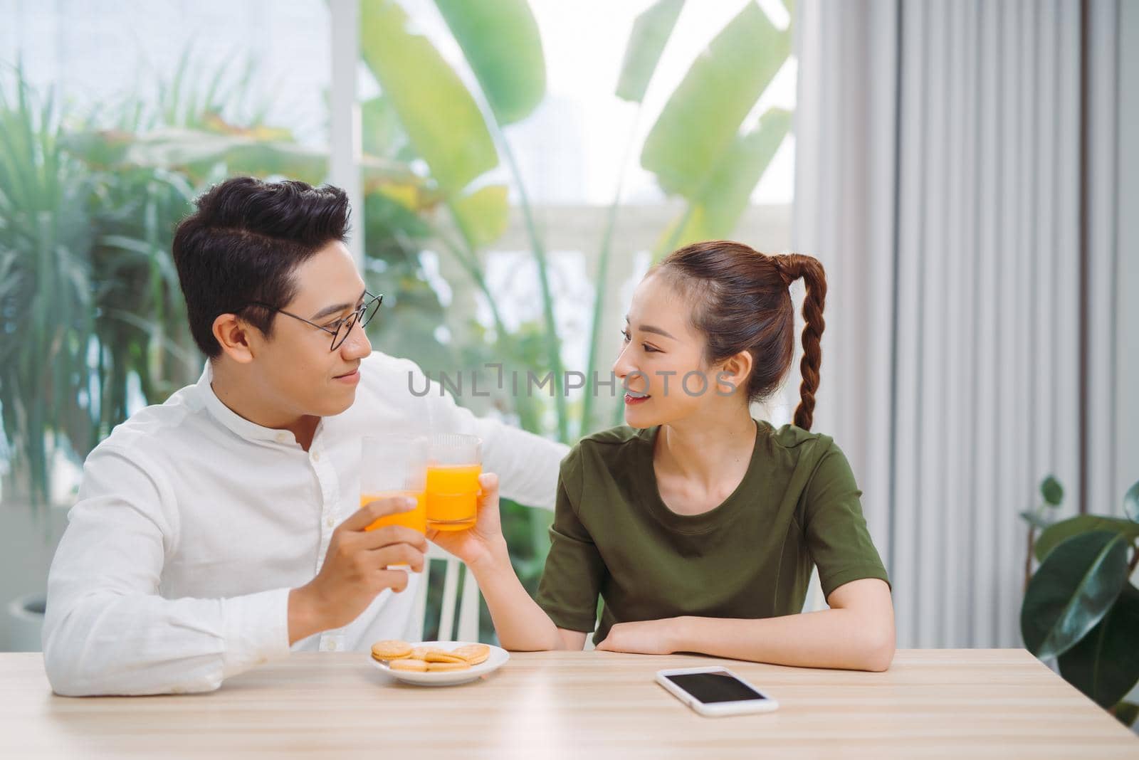 Loving man and woman drinking fresh orange juice enjoying pleasant morning cooking together, healthy meal and lifestyle concept