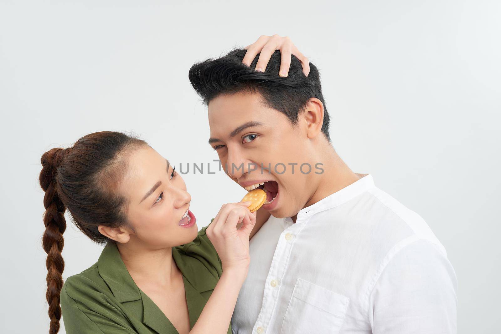 Gorgeous fun couple feeding eachother cookies over white