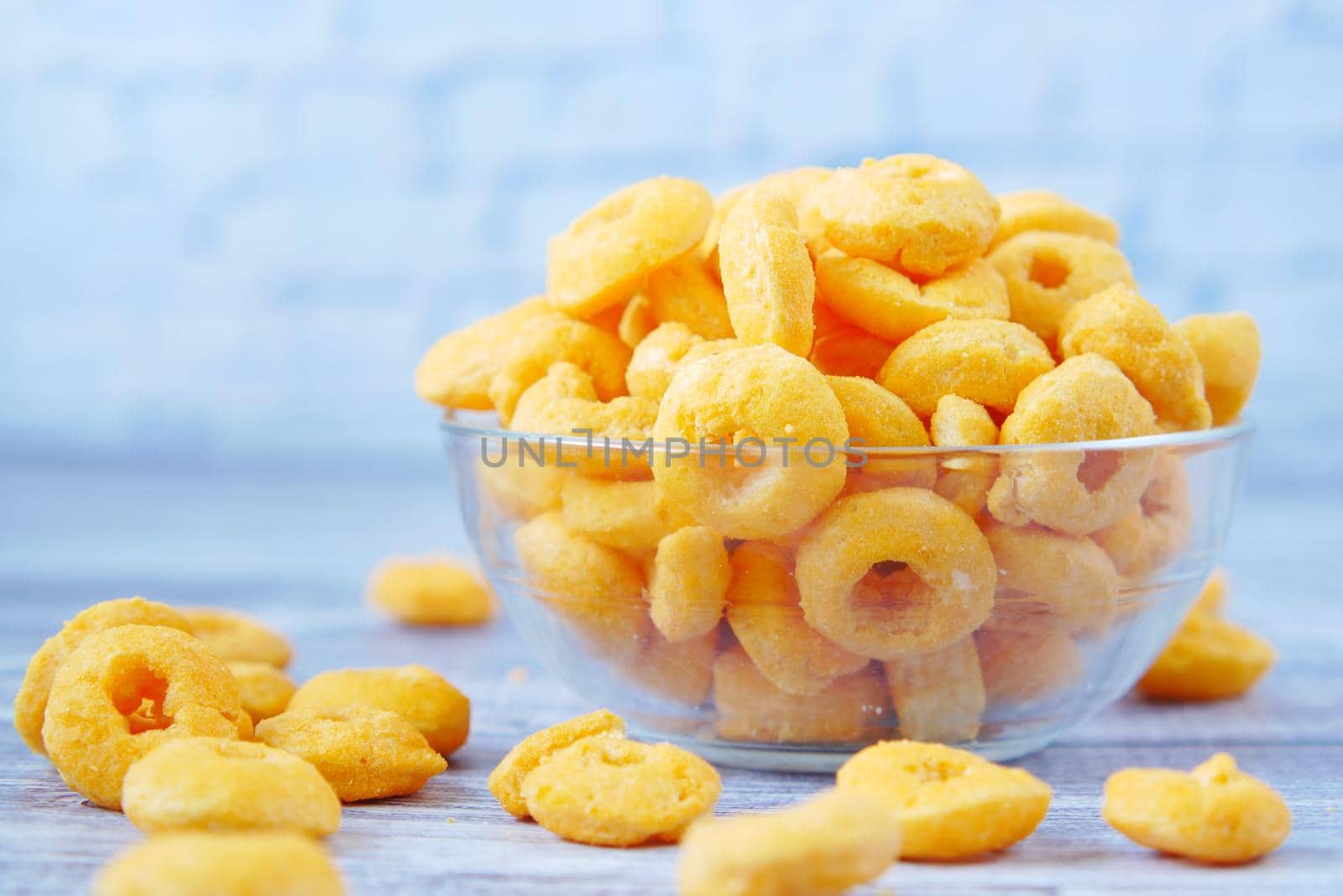 puffed corn rings chips in black bowl on white background,