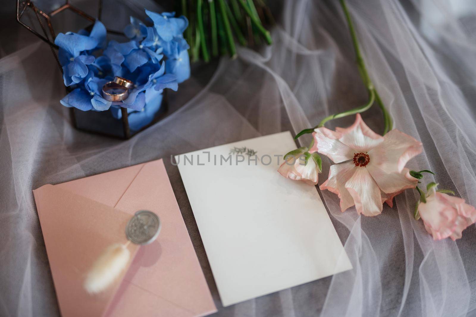 wedding invitation in a gray envelope on a table with green sprigs