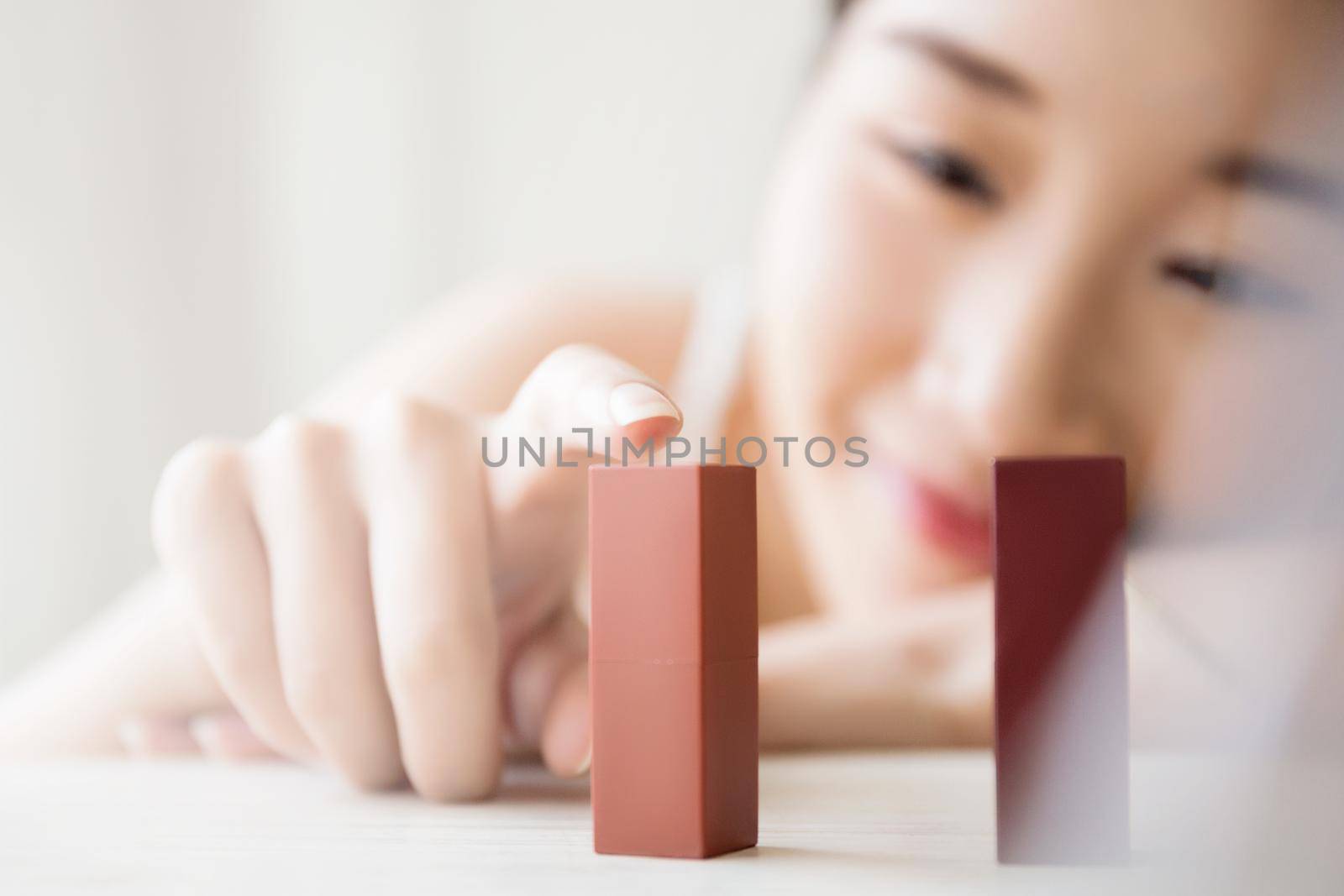 Beauty Concept - Beautiful asian woman choosing lipsticks in her bedroom by Benzoix