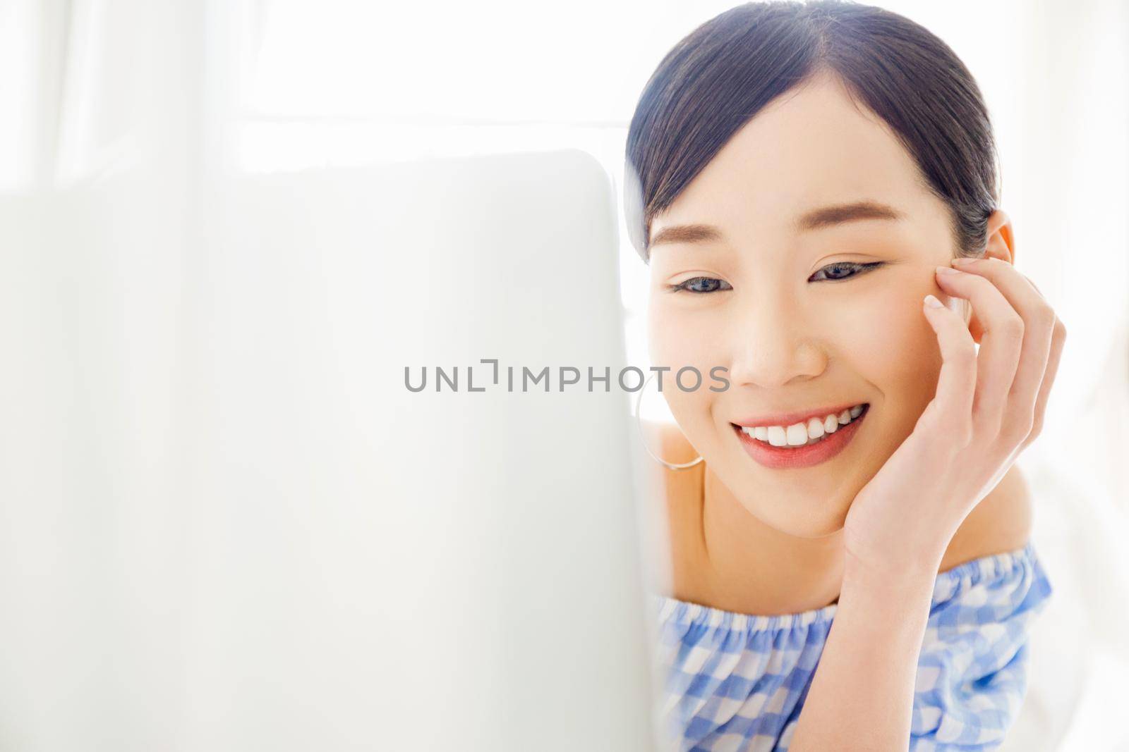 Happy young Asian woman using digital labtop computer in bedroom.