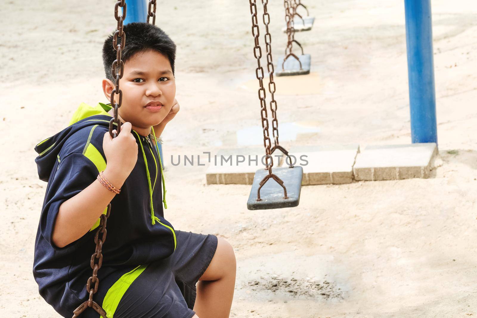 Happy asian sport boy play on swing playground in Garden
