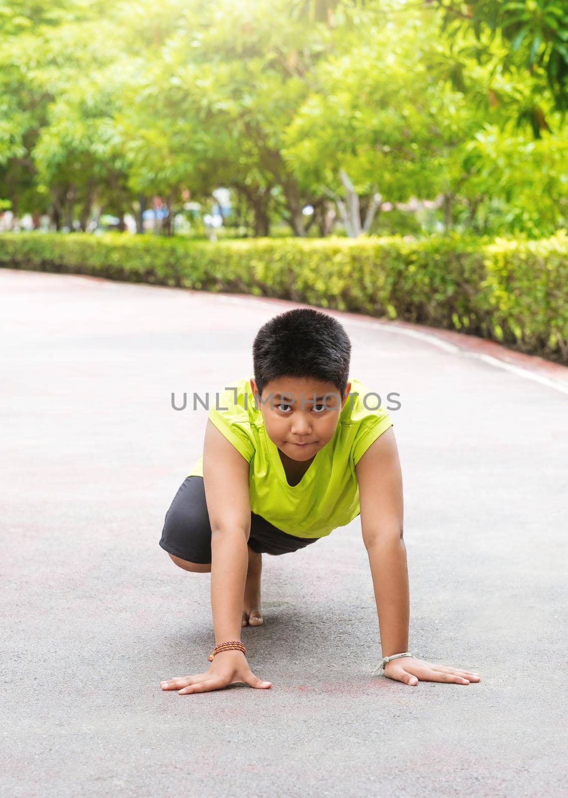 Young Asian boy prepare to start running on track in the garden during day time to practice himself